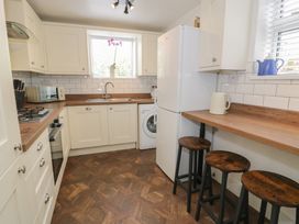 A kitchen with appliances and stools at 4 Haven Villas in Conwy