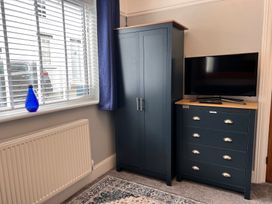 A wardrobe and chest of drawers with television in a bedroom at Mid Haven Cottage Conwy