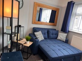 A living room with a blue sofa and lamp at Mid Haven Cottage in Conwy