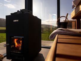 A stove with flames and a bucket in a room at Low Longlands in Cartmel