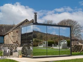 A glass structure with a chimney in a field at Middle Longlands in Cartmel