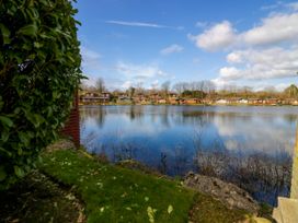 View of a lake with cabins along the shore at Loluke Lodge on The Lake, 5 Coniston Drive, Borwick near Carnforth