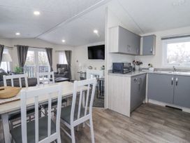 A living room and kitchen area with a table and chairs at Lazy Daze in Carnaby near Bridlington