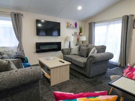 A living room with a sofa and television at Brighter Daze in Carnaby near Bridlington