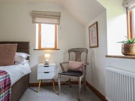 A bedroom with a bed, nightstand, chair, and window at Cwmwr in Penybontfawr