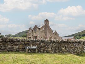 A house and stone wall with a sign at Cwmwr in Penybontfawr