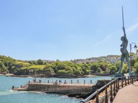 A waterfront with a statue holding a sword and people on a pier at Munro Lodge in Woolsery near Woolfardisworthy