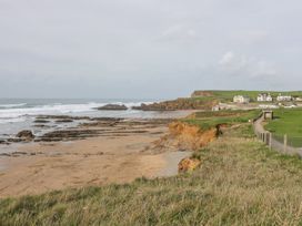 A coastal scene with a sandy beach rocks grassy cliffs and houses on the right at Munro Lodge in Woolsery near Woolfardisworthy
