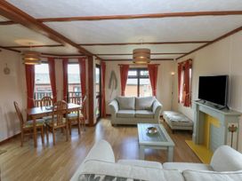 A living room with a dining area and television at 16 Forest Lodge in Chwilog