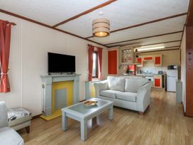 A living room with a television and sofa at 16 Forest Lodge in Chwilog