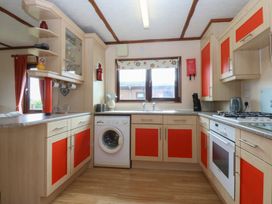 A kitchen with a washing machine and stove at 16 Forest Lodge in Chwilog
