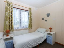 A bedroom with two single beds and nightstands at 16 Forest Lodge in Chwilog