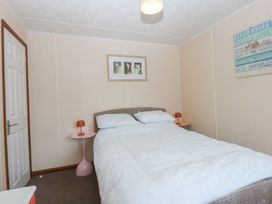 A bedroom with a bed and bedside table at 16 Forest Lodge Chwilog