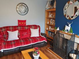 A living room with a sofa, shelf and decorative items at Normandy in Nefyn