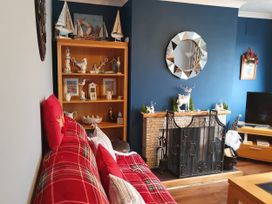 A living room with a shelf, sofa and fireplace at Normandy in Nefyn
