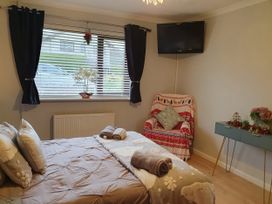 A bedroom with a bed and chair at Normandy in Nefyn
