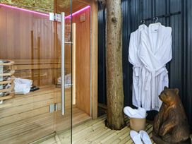 A sauna with wooden bench, robes, slippers and a bear statue at The Nest in Prestatyn