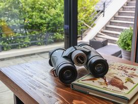 A wooden table with binoculars and a bird guide book at The Nest in Prestatyn