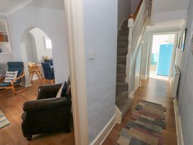 A hallway with a staircase and armchairs at Longmoor in Tenby