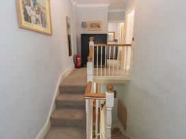 A hallway with stairs and framed artwork at Longmoor, Tenby