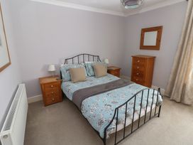 A bedroom with a bed and nightstands at Longmoor in Tenby