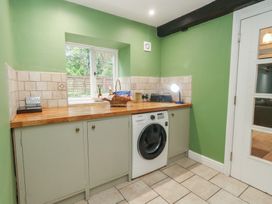 A kitchen with a washing machine and wooden counter at The Grain Store in Weymouth