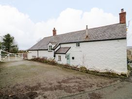 A white stone house with a slate roof and two chimneys next to a gravel driveway at Ty Croes in St George near Bodelwyddan