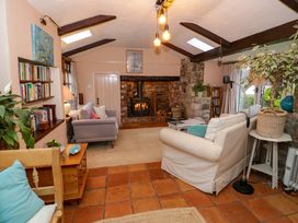 A living room with sofas a wood-burning stove bookshelves and plants at Ty Croes in St George near Bodelwyddan