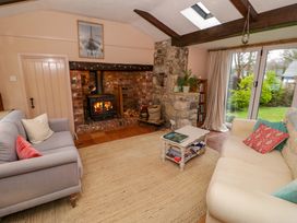 A living room with two sofas a coffee table a wood burning stove and glass doors leading to a garden at Ty Croes in St George near Bodelwyddan
