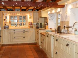 A kitchen with wooden cabinets tiled floor and a window with various kitchen utensils at Ty Croes St George near Bodelwyddan