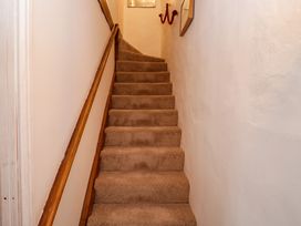 A staircase with brown carpet and wooden handrail between white walls at Ty Croes St George near Bodelwyddan