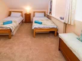 A bedroom with two single beds a wooden cabinet a window seat and shelves at Ty Croes in St George near Bodelwyddan
