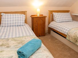 A bedroom with two single beds a wooden nightstand with a lamp and a rolled blue towel on a bed at Ty Croes in St George near Bodelwyddan