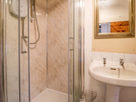 A bathroom with a shower enclosure a white sink and a mirror at Ty Croes in St George near Bodelwyddan