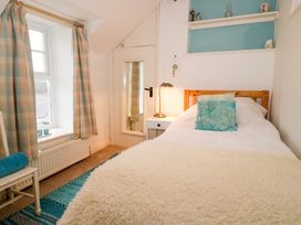 A bedroom with single bed and pillows beside a window with curtains at Ty Croes in St George near Bodelwyddan