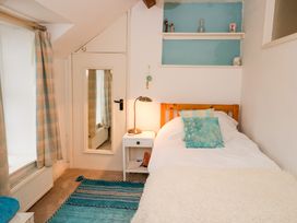 A bedroom with a single bed a bedside table with lamp and a mirror on a door at Ty Croes in St George near Bodelwyddan