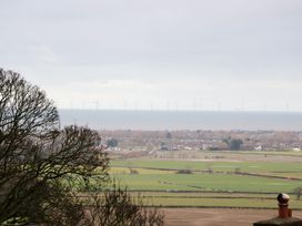 A rural landscape with trees fields houses and wind turbines in the sea at Ty Croes in St George near Bodelwyddan