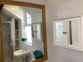 A bathroom with a shower cubicle a sink a mirror with a wooden frame and a white cabinet with mirrored doors at Ty Croes in St George near Bodelwyddan