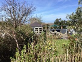 A garden with a small shed a patio with a table and chairs and various plants at Ty Croes in St George near Bodelwyddan