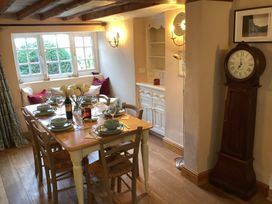 A dining room with a wooden table set for six near a window and a grandfather clock at Ty Croes in St George near Bodelwyddan