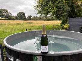A hot tub with champagne and glasses in an outdoor setting at Wood Brook Cottage in Crowan