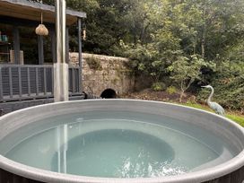 A hot tub with a flue pipe and stone wall at Wood Brook Cottage in Crowan
