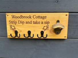 A wooden sign with hooks and a bottle opener at Wood Brook Cottage in Crowan