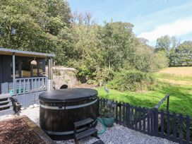 A garden area with a hot tub and deck at Wood Brook Cottage in Crowan