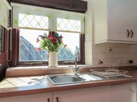 A kitchen sink with a dish rack and a vase of flowers on the windowsill at Beaconsfield Cottage in Burniston near Scalby