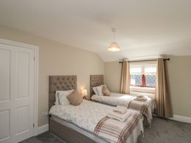 A bedroom with two single beds each with folded towels on a blanket near a window with curtains at Beaconsfield Cottage in Burniston near Scalby