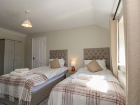 A bedroom with two single beds a nightstand with a lamp and a wardrobe at Beaconsfield Cottage in Burniston near Scalby