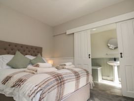 A bedroom with a bed covered in a plaid blanket and towels with an adjoining bathroom visible through sliding doors at Beaconsfield Cottage in Burniston near Scalby