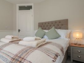 A bedroom with a bed with folded towels pillows a lamp on a bedside table and a closed white door at Beaconsfield Cottage in Burniston near Scalby