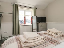 A bedroom with folded towels on bed a window with curtains a mirror a chest of drawers and a television at Beaconsfield Cottage in Burniston near Scalby